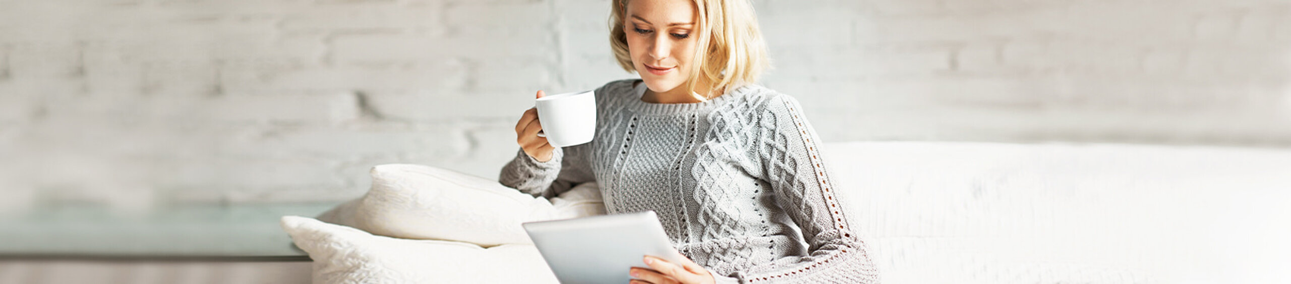 Frau informiert sich am Tablet und sitz auf dem Sofa
